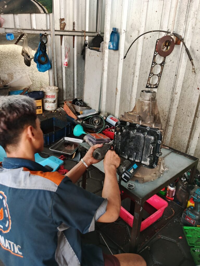 Mekanik memeriksa transmisi mobil matic saat perawatan dan ganti oli matic berkala
